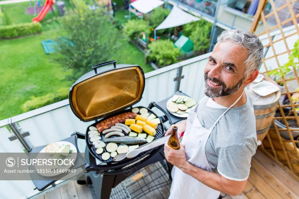 Smiling man barbecuing on his balcony