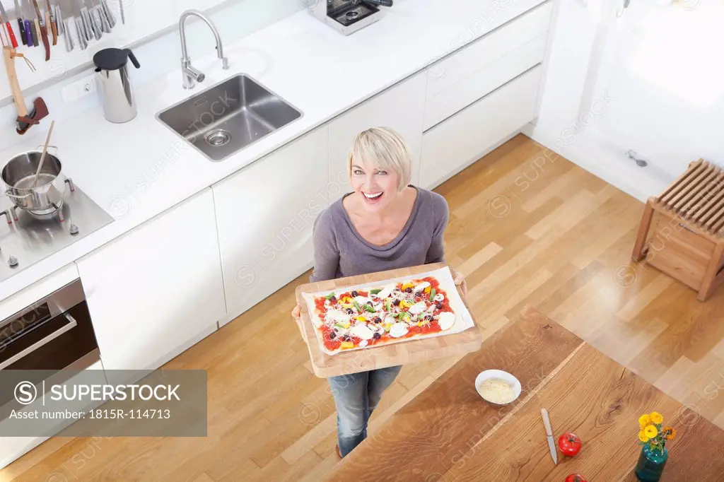 Germany, Bavaria, Munich, Woman preparing pizza in kitchen