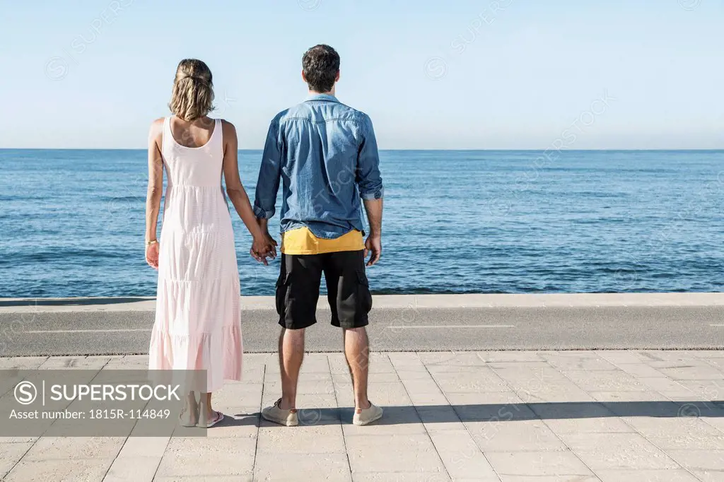 Spain, Mid adult couple standing at Atlantic Ocean, looking at view