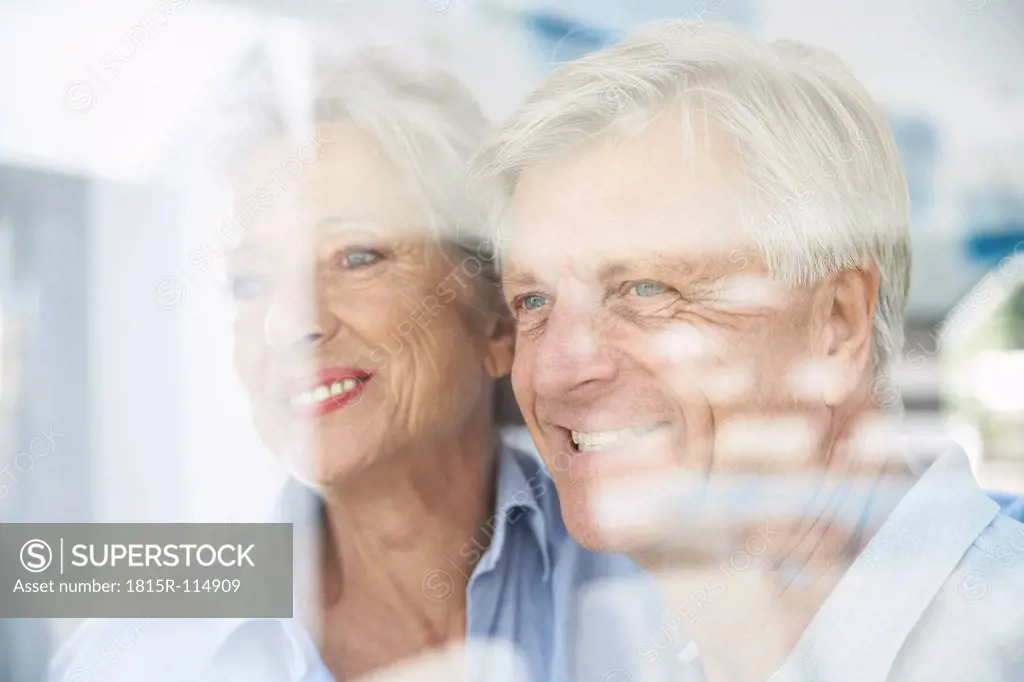 Spain, Senior couple behind window, smiling