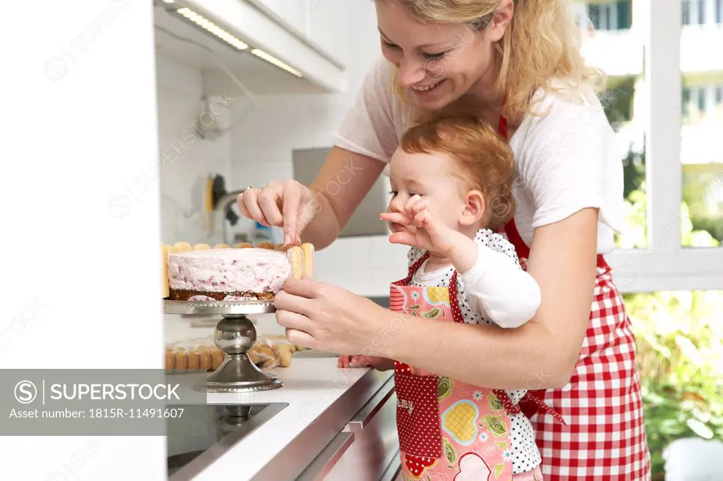 Mother and little daughter baking cake together in their kitchen