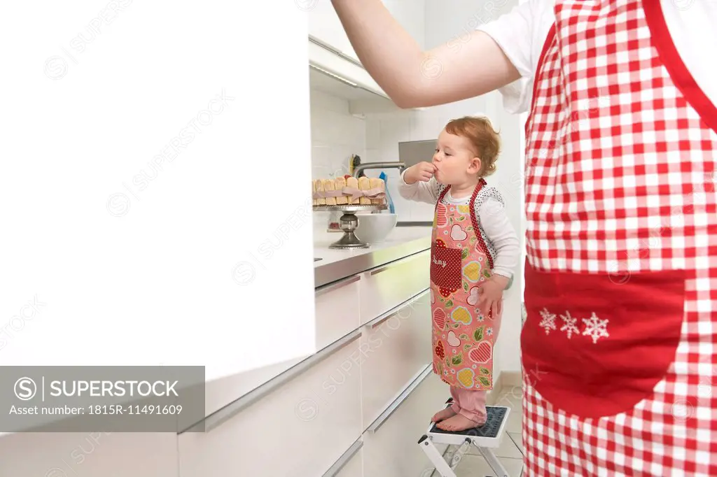 Mother and little daughter baking cake together in their kitchen