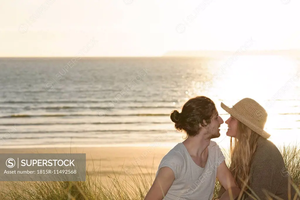 Young couple sitting at beach dunes in front of Atlantic