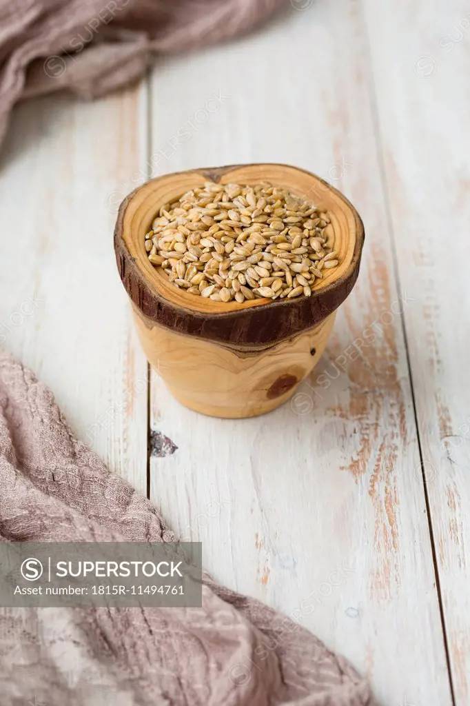 Bowl of Einkorn wheat, Triticum monococcum, on light wood