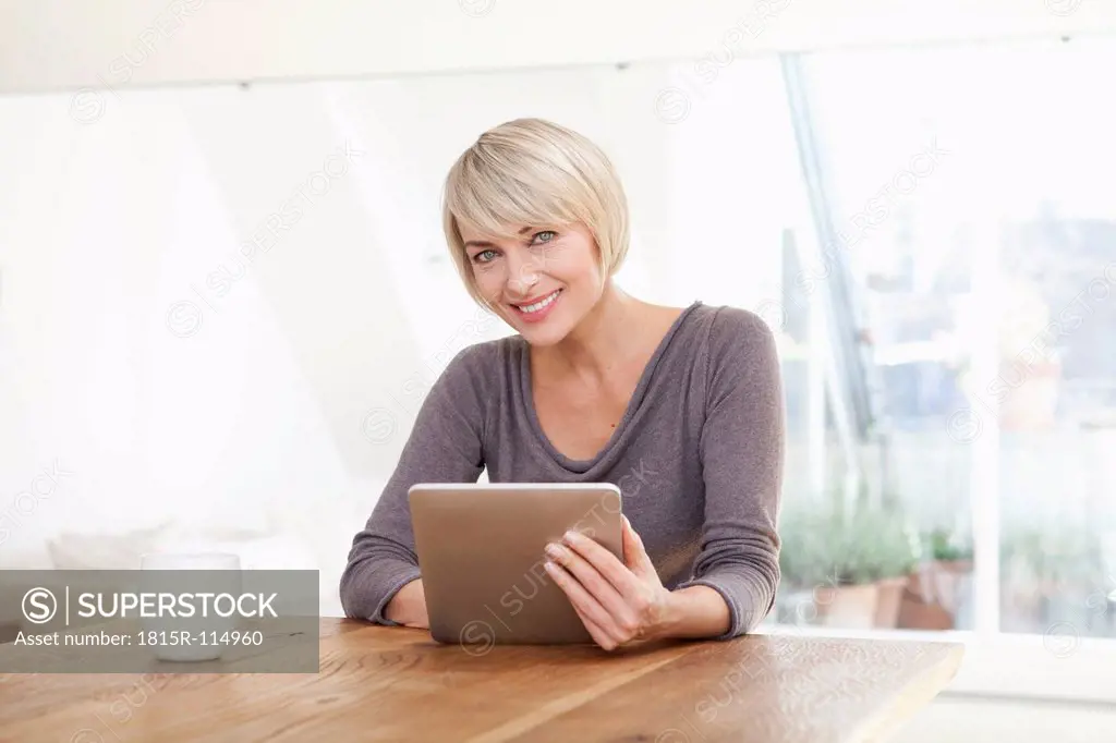 Germany, Bavaria, Munich, Woman using digital table at table, smiling, portrait