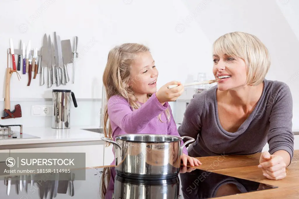 Germany, Bavaria, Munich, Daughter feeding mother in kitchen, smiling