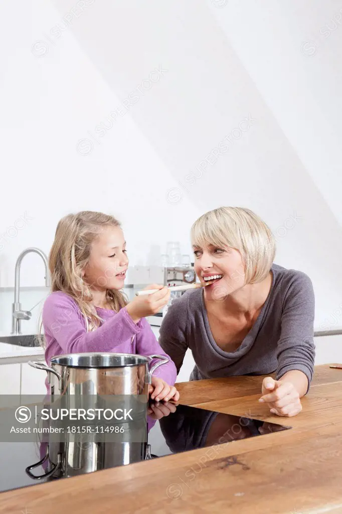 Germany, Bavaria, Munich, Daughter feeding mother in kitchen, smiling