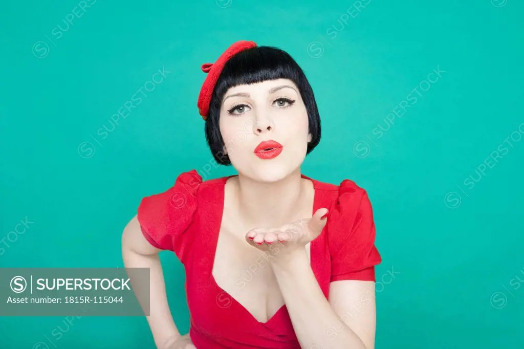 Close up of young woman blowing kiss against green background