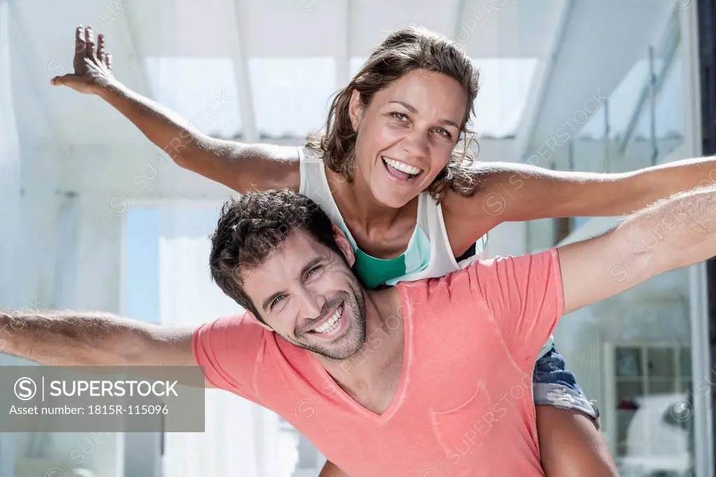 Spain, Mid adult man giving piggy back ride to woman, smiling