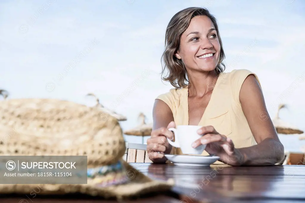 Spain, Mid adult woman in cafe with straw hat