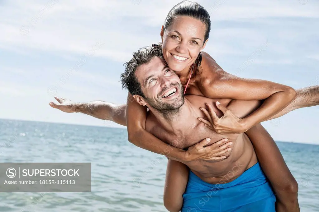 Spain, Mid adult man giving piggy back ride to woman