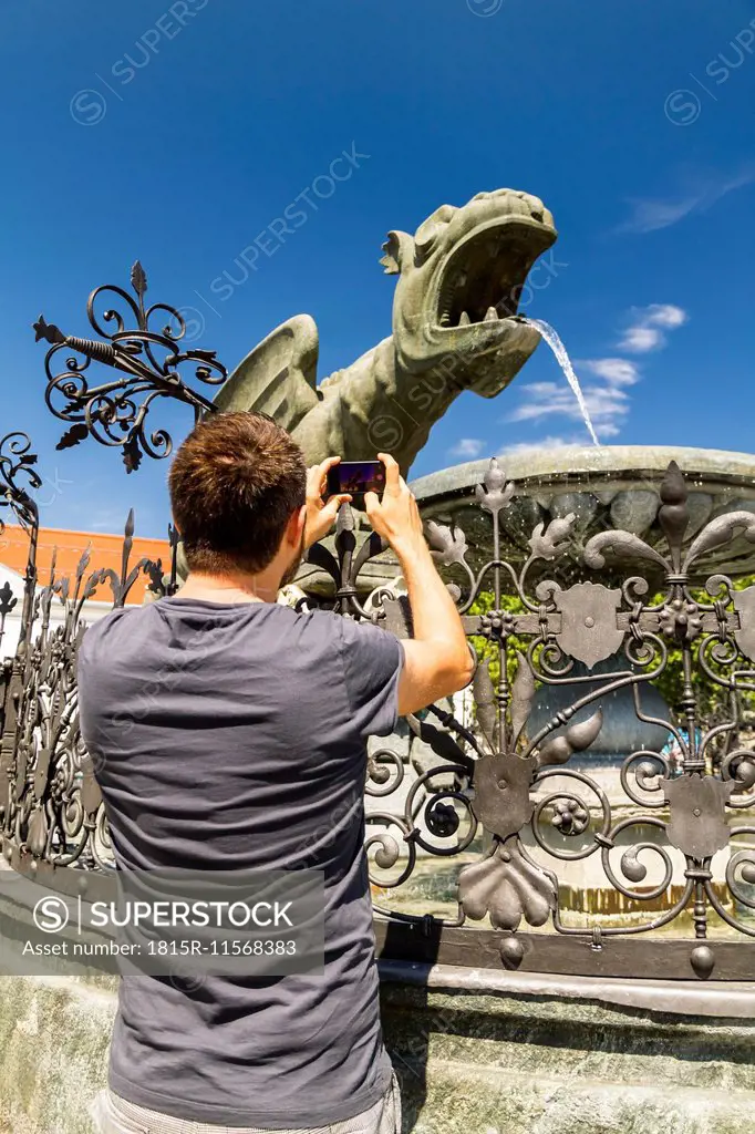 Austria, Klagenfurt, Man taking picture of Lindworm fountain