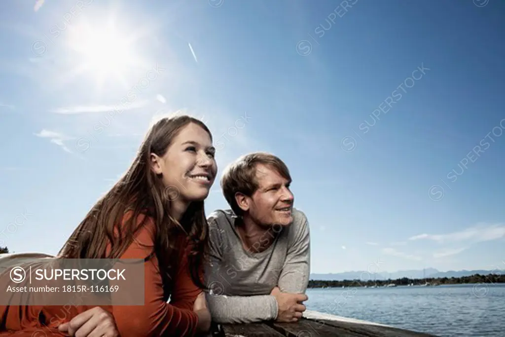 Germany, Bavaria, Couple lying on jetty at Lake Starnberg