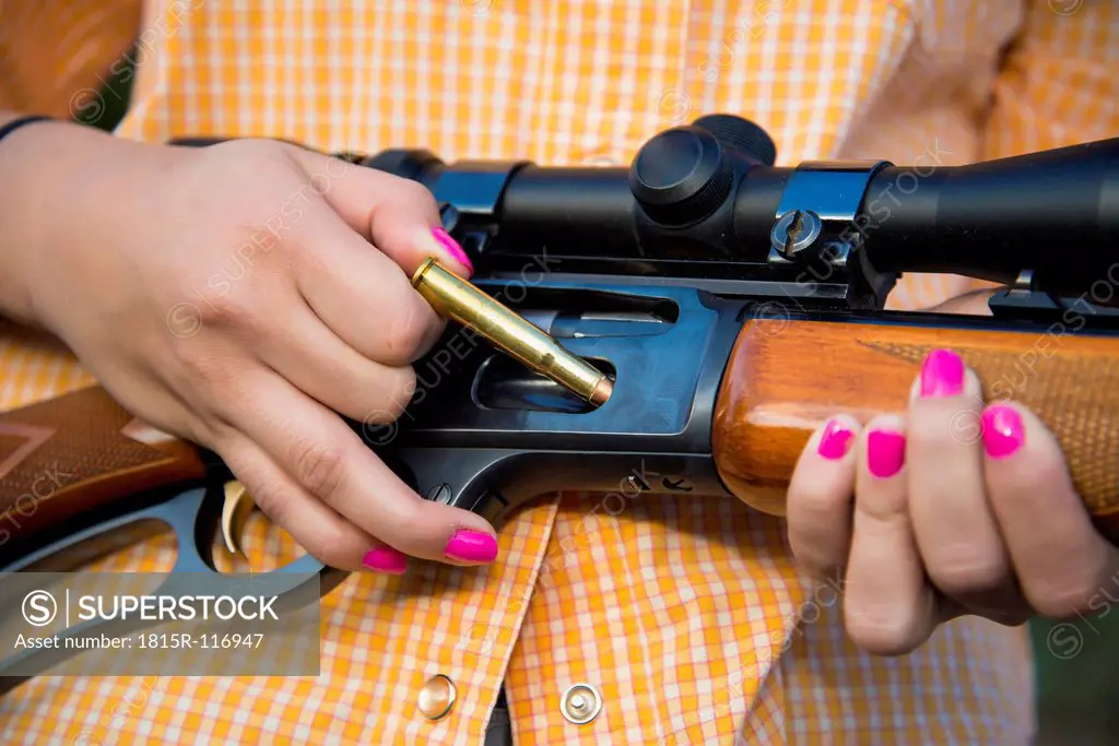 USA, Texas, Young woman inserting bullet in hunting rifle