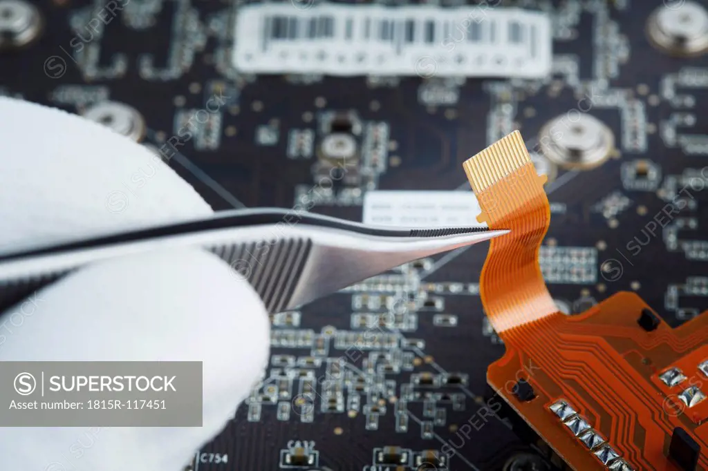 Human hand repairing printed circuit board, close up