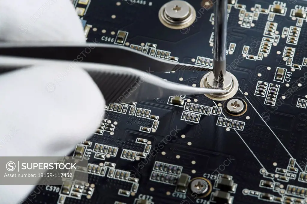 Human hand repairing printed circuit board, close up