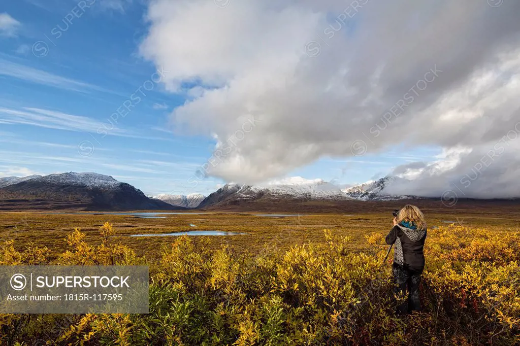 USA, Alaska, Tourist taking photograph of Alaska Range in autumn