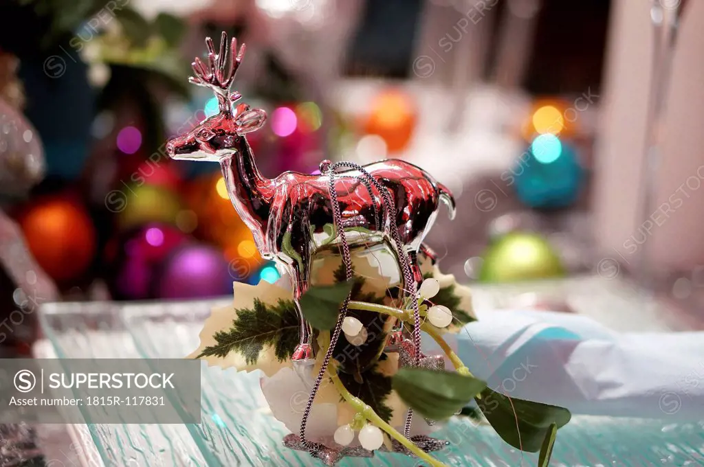 Christmas decoration with glass reindeer on dinner table, close up
