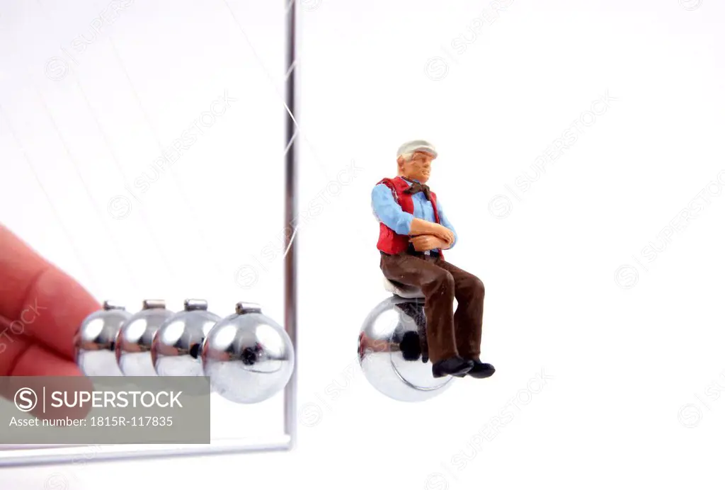 Figurine of old man ejected by newton´s cradle, close up