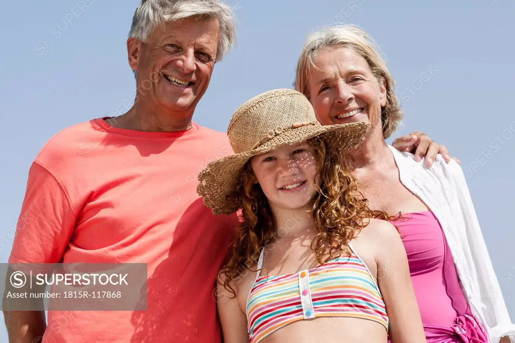 Spain, Grandparents with granddaughter at beach, smiling, portrait