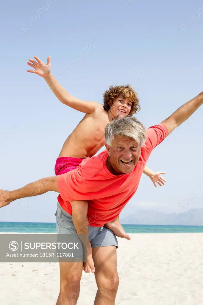 Spain, Grandfather giving piggyback ride to grandson, smiling