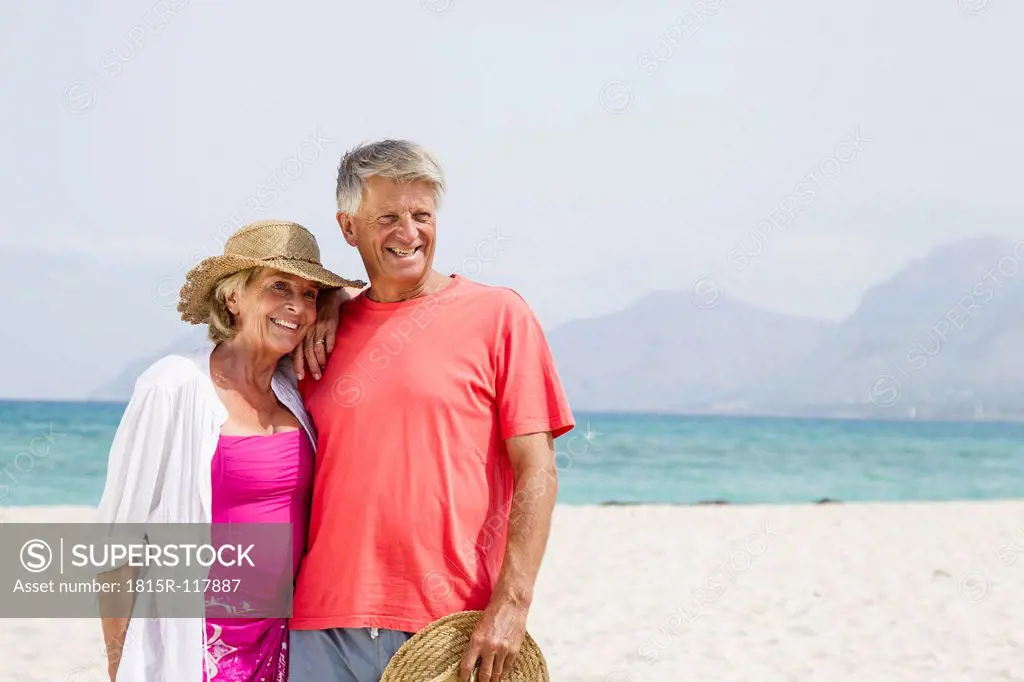 Spain, Senior couple standing at beach, smiling