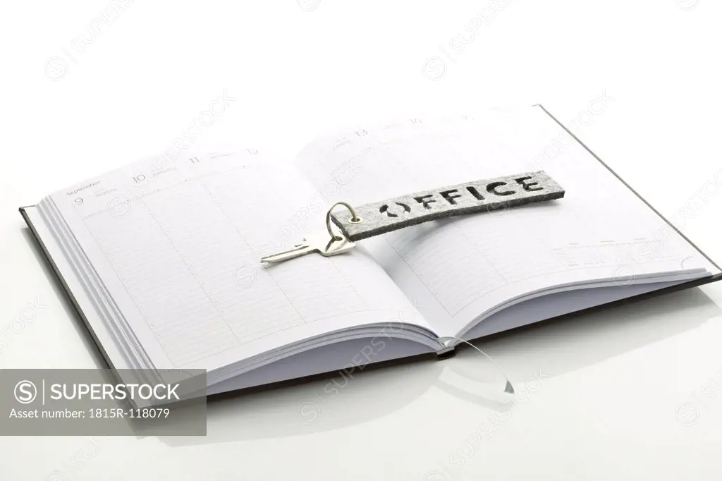 Close up of office key and appointment book on white background