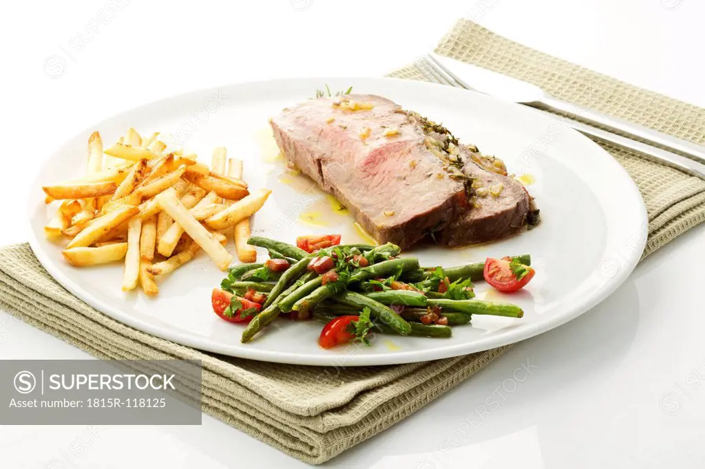 Roast beef, green beans and french fries on plate, close up