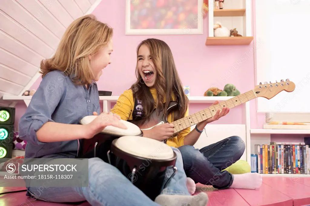 Girls playing guitar and drums, laughing