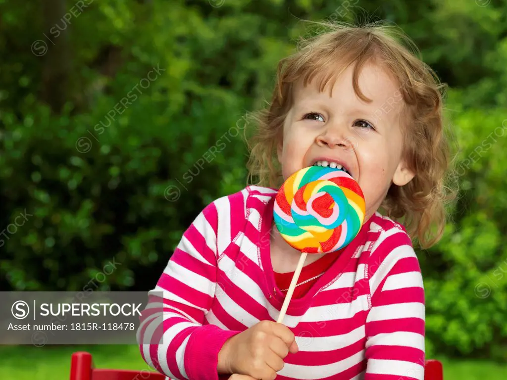 Germany, Duesseldorf, Girl sitting outside and eating lollipop