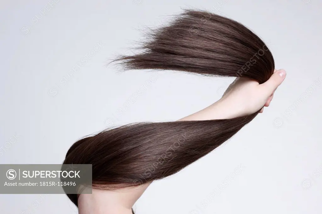 Human hand holding brown hair against white background, close up