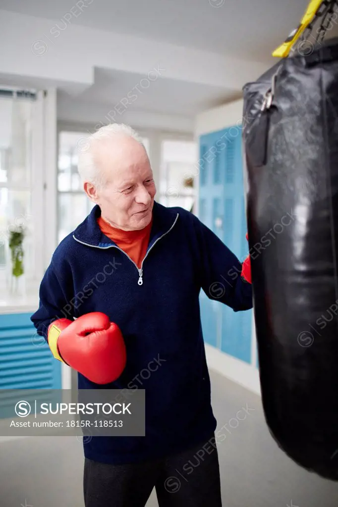 Germany, Duesseldorf, Senior man with boxing glove and punch bag