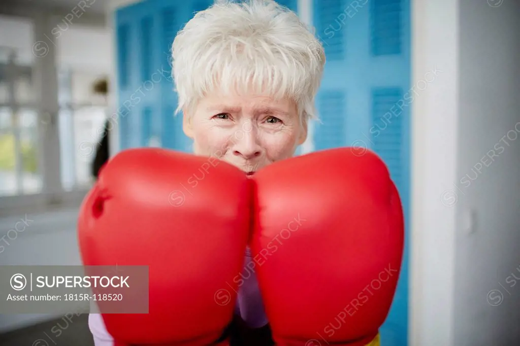 Germany, Duesseldorf, Portrait of senior woman with boxing glove