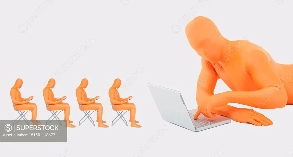 Men in orange zentai using laptop and digital tablet