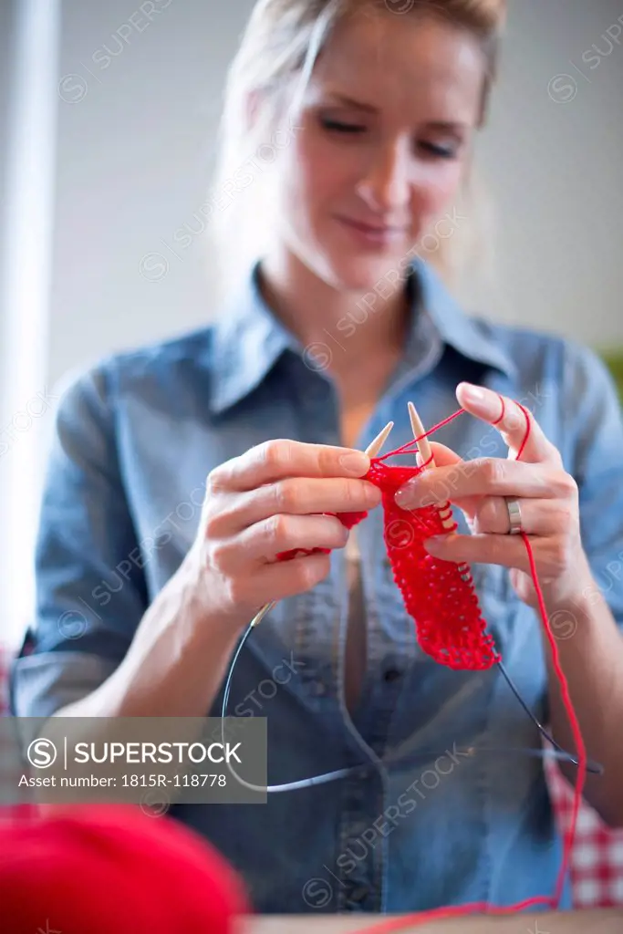Young woman knitting with red yarn