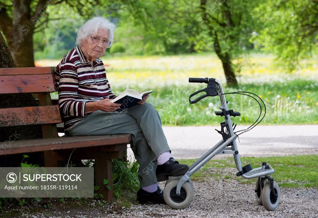 Austria, Senior woman sitting on bench and reading book