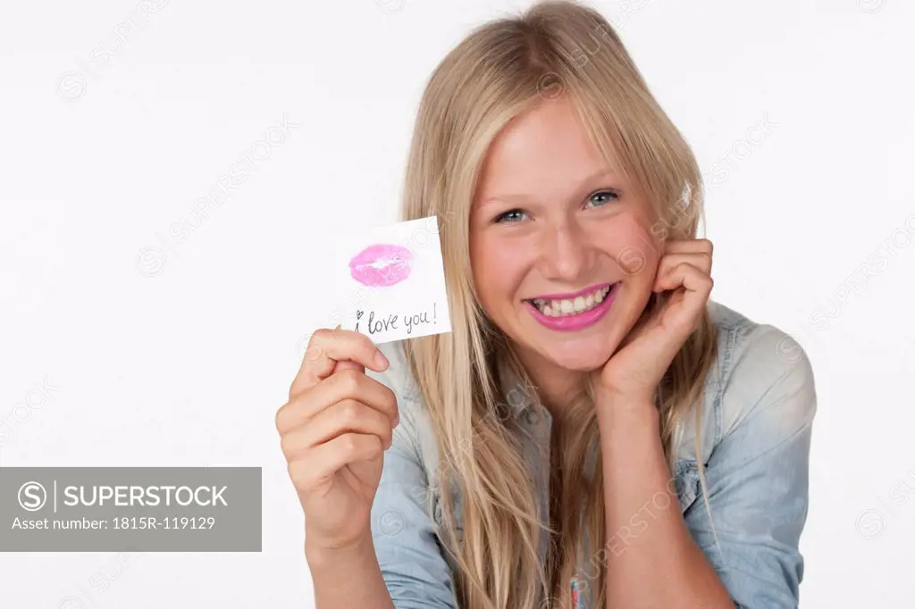 Teenage girl holding a piece of paper with lipstick imprint, smiling
