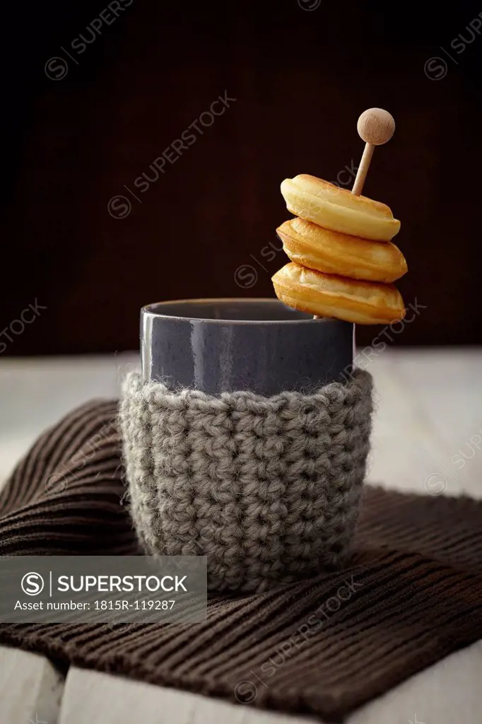 Baked doughnuts with cup and warmer on table