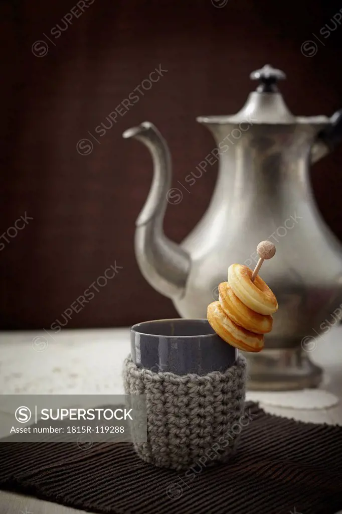 Baked doughnuts with cup, tea pot and warmer on table