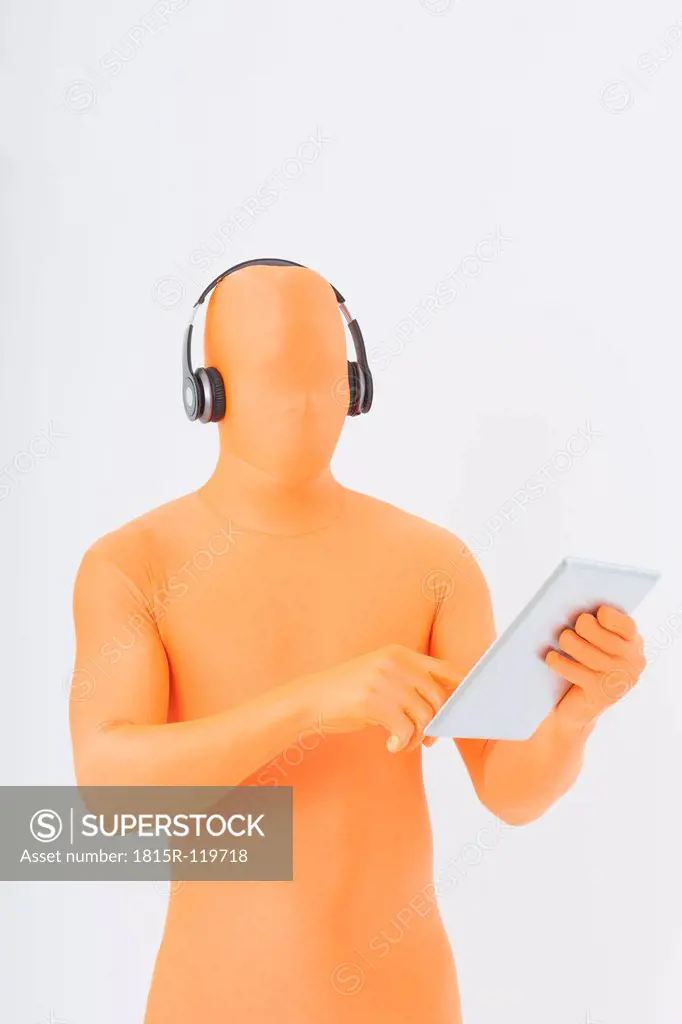 Mature man in orange zentai listening music and using digital tablet