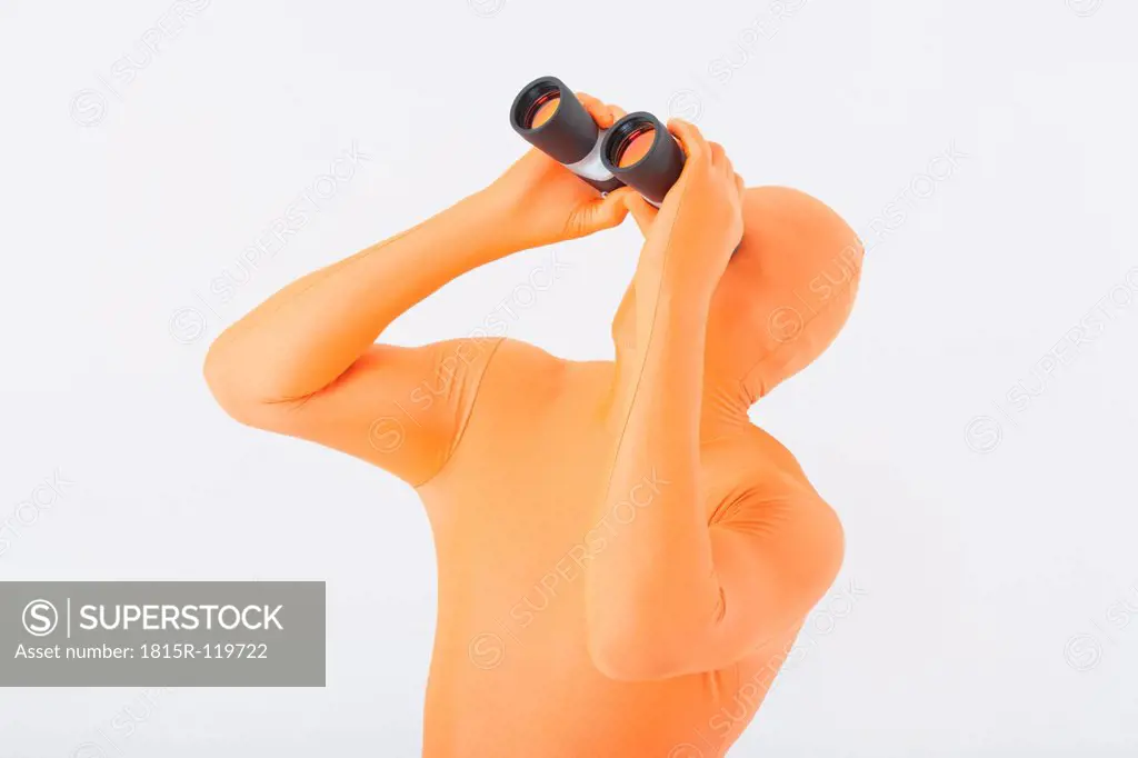 Mature man in orange zentai with binoculars against white background