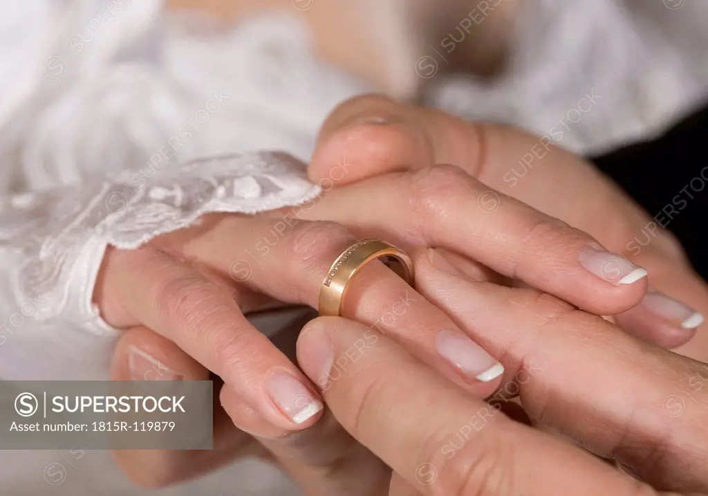 Man inserting wedding ring to wife, close up