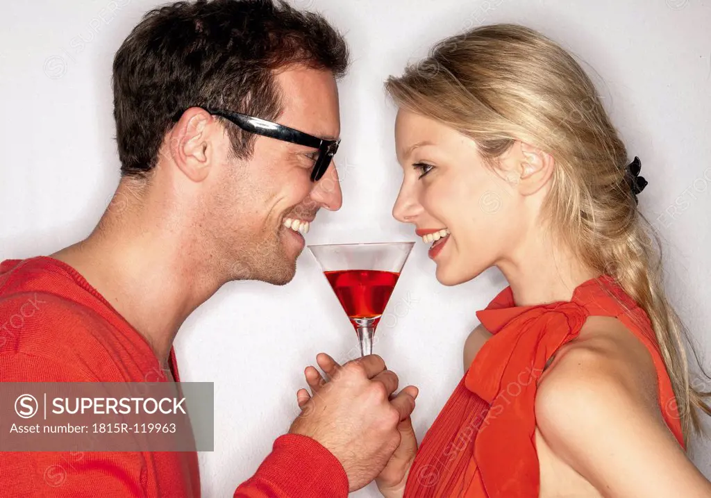 Couple sharing cocktail against white background, close up