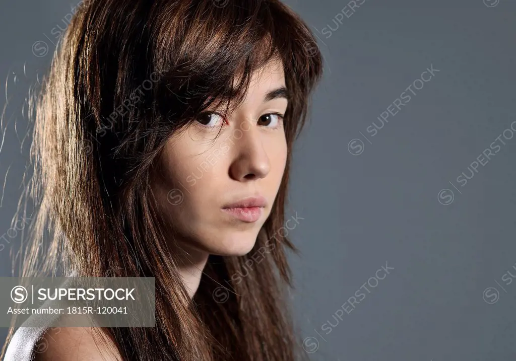 Portrait of young woman against gray background, close up
