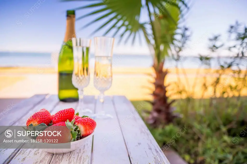 USA, Texas, Bowl of strawberries and champagne on beach with palm tree