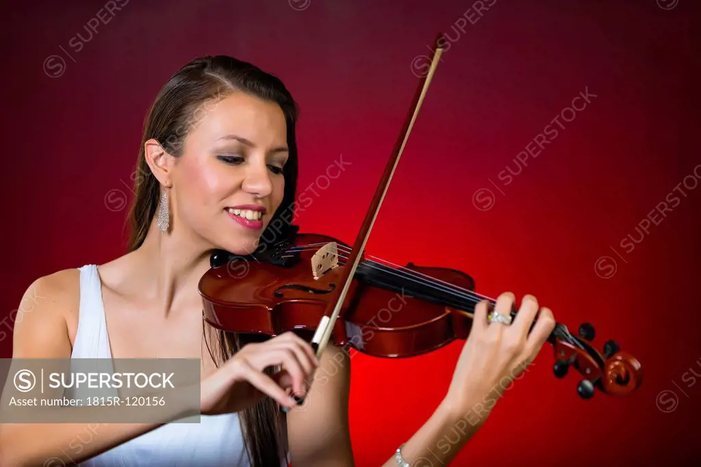 Young woman playing violin, smiling