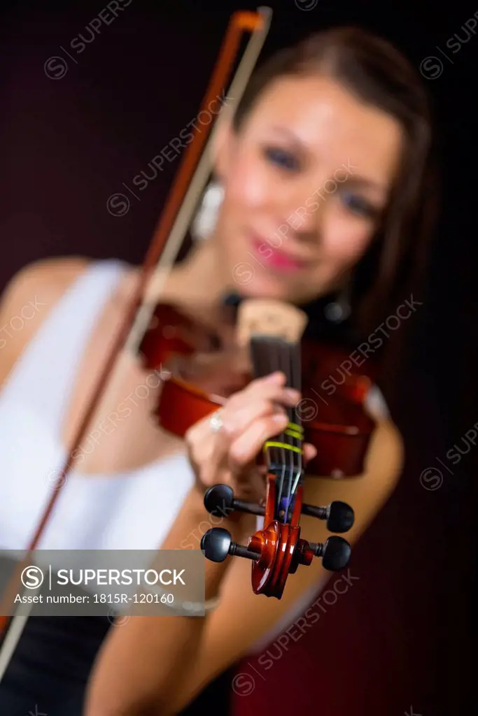 Young woman playing violin, smiling