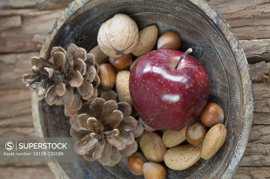 Apple, nuts and pine cones for christmas in bowl on table