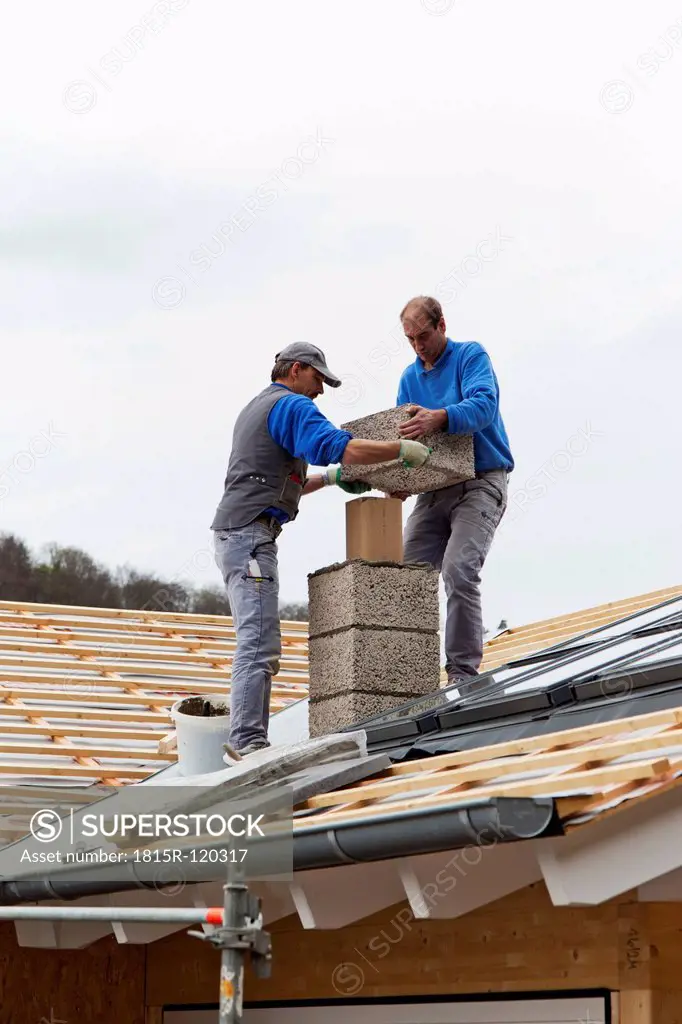 Europe, Germany, Rhineland Palatinate, Workers installing chimney on roof top