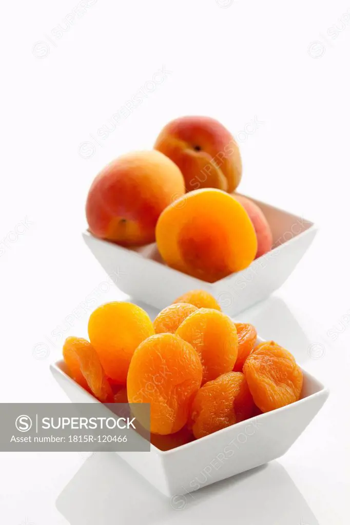 Fresh and dried apricots in bowl on white background, close up